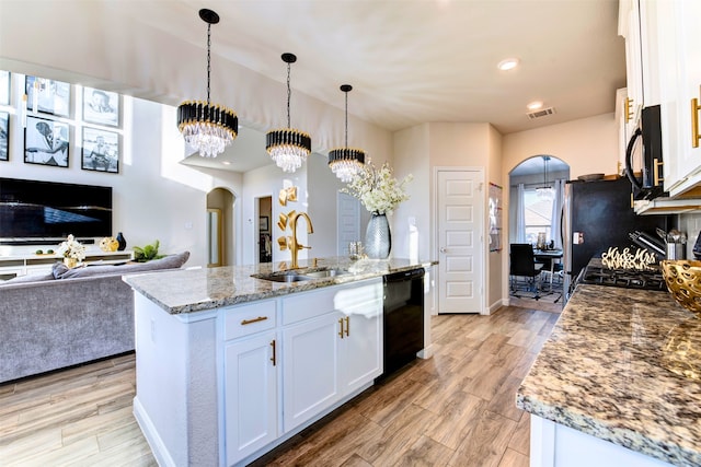 kitchen featuring sink, pendant lighting, a chandelier, a center island with sink, and white cabinets