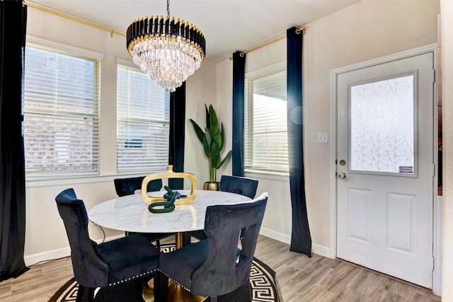 dining space with light hardwood / wood-style floors and a notable chandelier