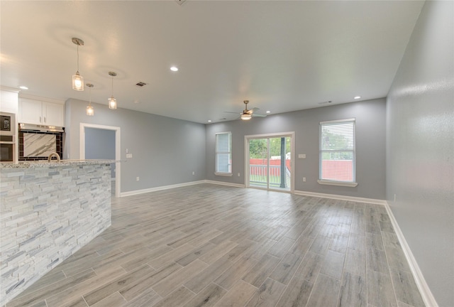 unfurnished living room featuring ceiling fan and sink