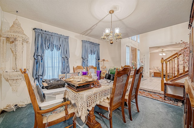 carpeted dining room with ceiling fan with notable chandelier and a textured ceiling