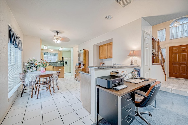 kitchen featuring kitchen peninsula, stainless steel fridge, and light tile patterned floors