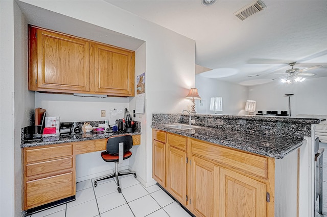 kitchen featuring sink, ceiling fan, dark stone countertops, light tile patterned floors, and kitchen peninsula