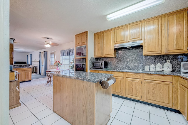 kitchen with extractor fan, light tile patterned floors, a kitchen island, and black appliances