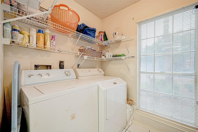 clothes washing area with tile patterned flooring, independent washer and dryer, and a textured ceiling