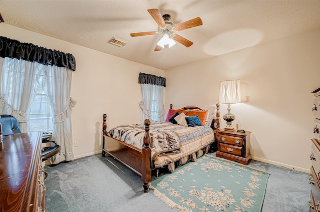 carpeted bedroom with ceiling fan and a textured ceiling