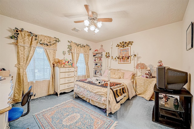 carpeted bedroom with ceiling fan and a textured ceiling