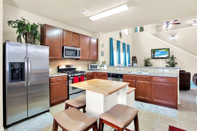 kitchen featuring a breakfast bar, sink, appliances with stainless steel finishes, tasteful backsplash, and kitchen peninsula