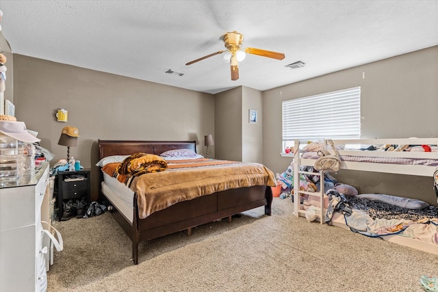 carpeted bedroom with ceiling fan and a textured ceiling