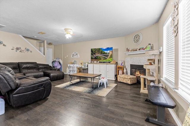 living room featuring dark hardwood / wood-style flooring and a stone fireplace