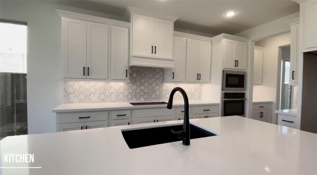 kitchen with stainless steel oven, built in microwave, sink, white cabinets, and tasteful backsplash