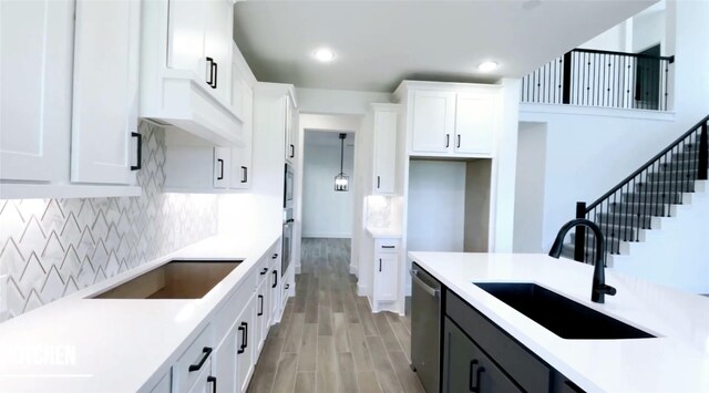 kitchen featuring appliances with stainless steel finishes, light hardwood / wood-style floors, pendant lighting, sink, and white cabinetry