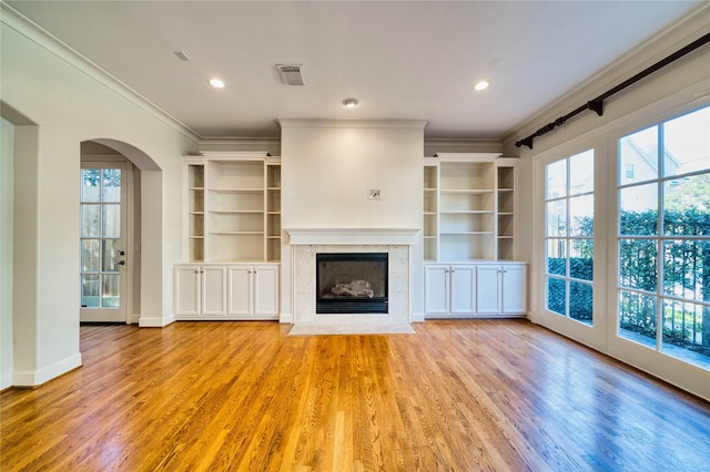 unfurnished living room with a fireplace, plenty of natural light, ornamental molding, and light hardwood / wood-style flooring