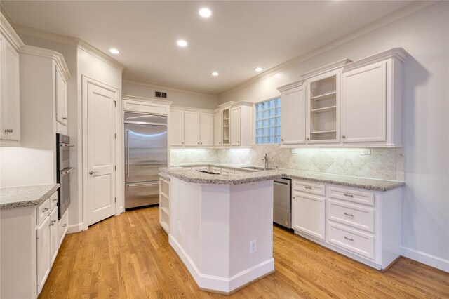 kitchen with light stone counters, a center island, white cabinets, and stainless steel appliances