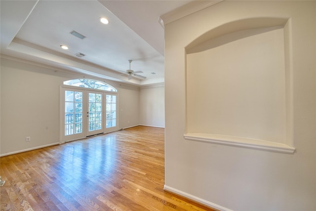 unfurnished room with french doors, light hardwood / wood-style flooring, a raised ceiling, and ceiling fan