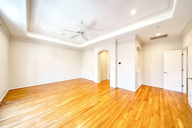 spare room with ceiling fan, ornamental molding, light hardwood / wood-style flooring, and a tray ceiling