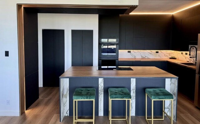 kitchen with sink, a breakfast bar area, a center island, light wood-type flooring, and black appliances