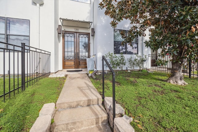 view of exterior entry featuring a yard and french doors