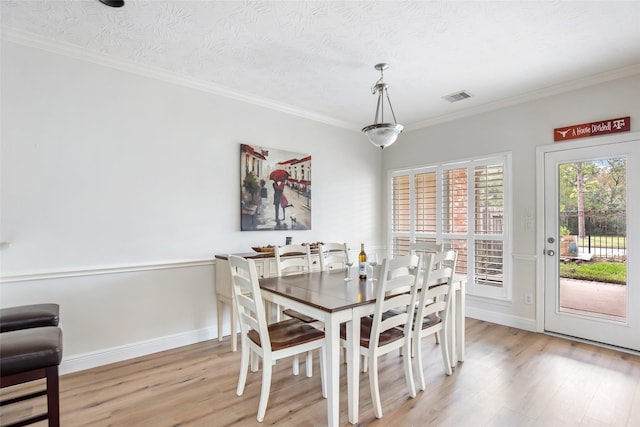 dining area featuring crown molding, light hardwood / wood-style floors, and a textured ceiling