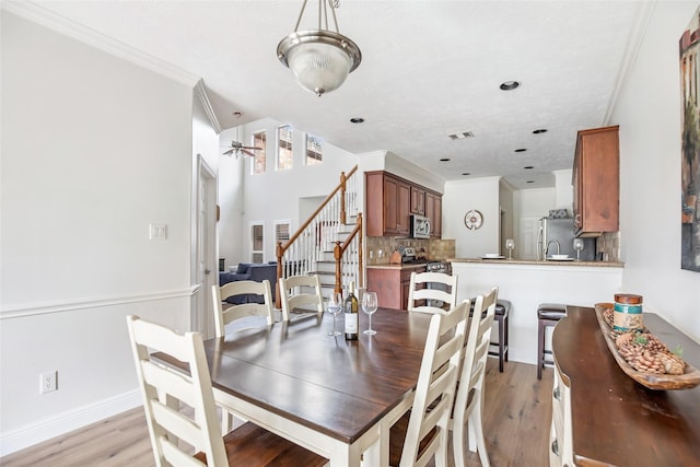 dining space featuring light hardwood / wood-style flooring, ceiling fan, and crown molding