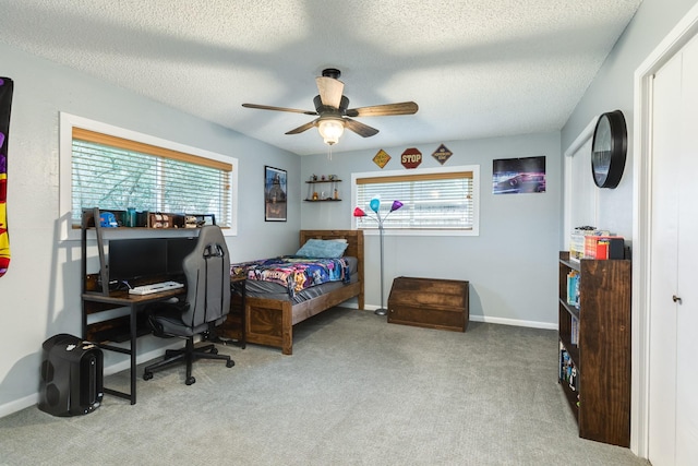 carpeted bedroom featuring ceiling fan and a textured ceiling