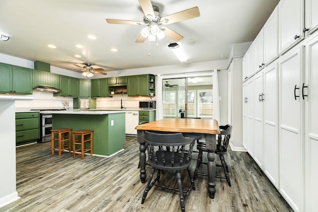 kitchen with a kitchen breakfast bar, green cabinets, a kitchen island, and appliances with stainless steel finishes