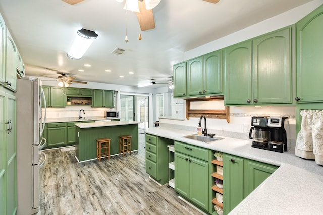 kitchen with green cabinets, a kitchen island, white refrigerator, and sink