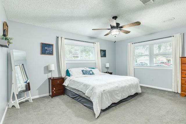 carpeted bedroom featuring ceiling fan and a textured ceiling