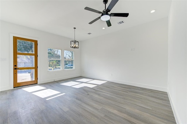 spare room featuring ceiling fan with notable chandelier and light hardwood / wood-style floors