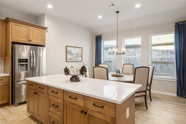 kitchen featuring pendant lighting, stainless steel fridge, a wealth of natural light, a notable chandelier, and a kitchen island