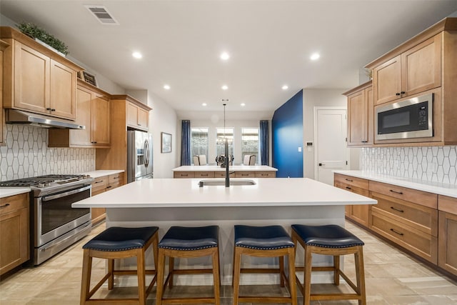 kitchen with backsplash, sink, an island with sink, a kitchen bar, and stainless steel appliances