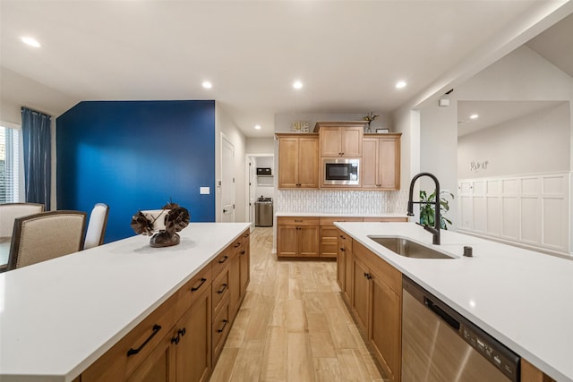 kitchen with a center island with sink, sink, vaulted ceiling, tasteful backsplash, and stainless steel appliances