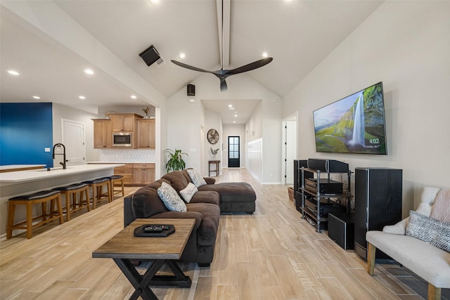 living room featuring beam ceiling, ceiling fan, sink, and high vaulted ceiling