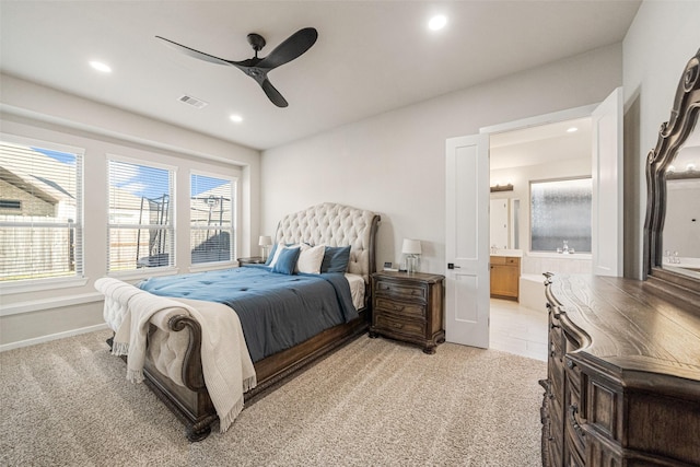 carpeted bedroom with ensuite bathroom and ceiling fan