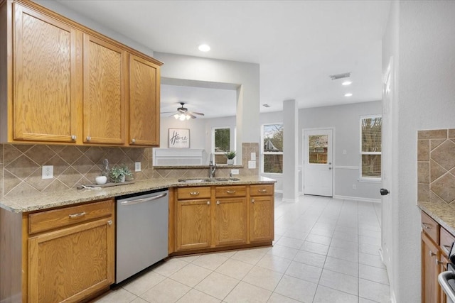 kitchen featuring backsplash, dishwasher, light stone counters, and sink