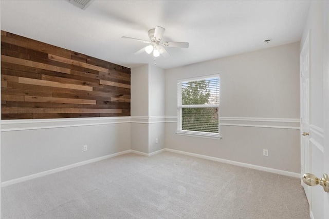 spare room featuring light colored carpet, ceiling fan, and wood walls