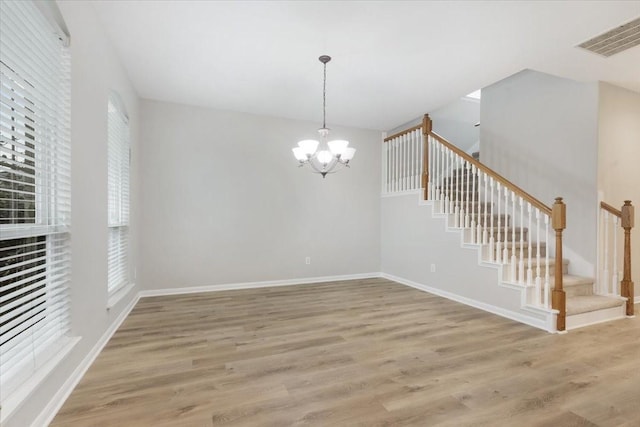 unfurnished dining area with a healthy amount of sunlight, hardwood / wood-style floors, and a chandelier