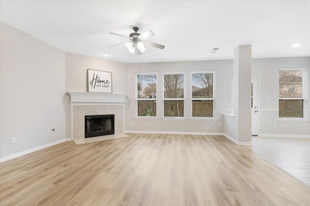 unfurnished living room with ceiling fan, a high end fireplace, and light wood-type flooring