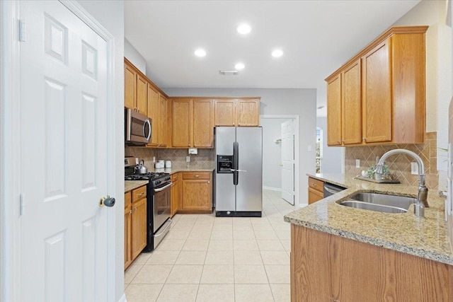 kitchen with light stone countertops, sink, decorative backsplash, light tile patterned floors, and appliances with stainless steel finishes