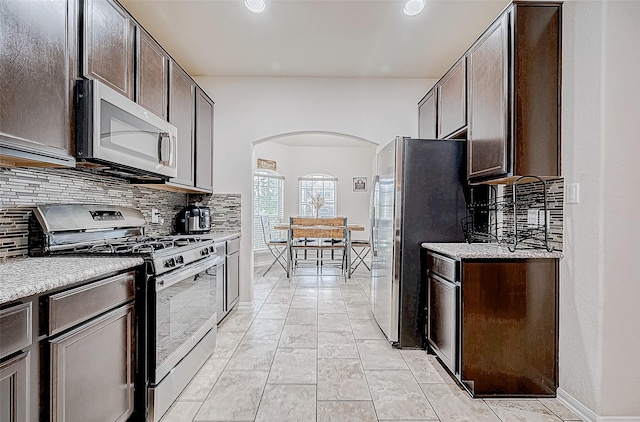 kitchen featuring decorative backsplash, dark brown cabinets, light tile patterned flooring, and appliances with stainless steel finishes