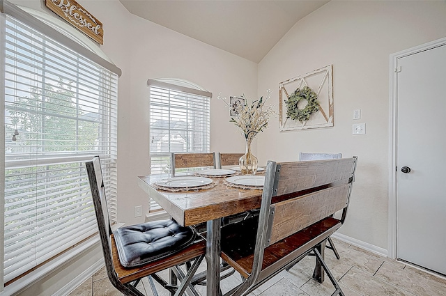 dining area with light tile patterned flooring and lofted ceiling