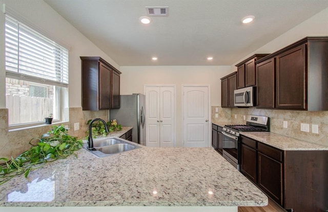 kitchen featuring backsplash, sink, stainless steel appliances, and a wealth of natural light