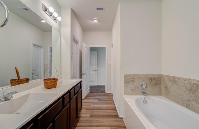 bathroom with vanity, a bath, and wood-type flooring