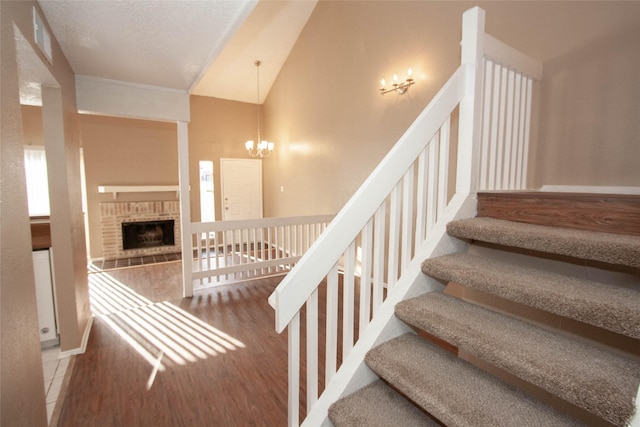 stairs with hardwood / wood-style floors, vaulted ceiling, a fireplace, and a chandelier