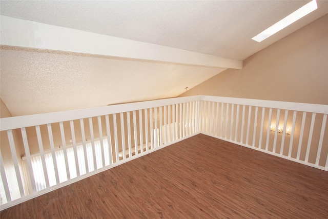 additional living space featuring vaulted ceiling with skylight and wood-type flooring