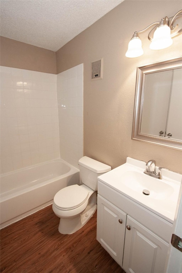 full bathroom featuring hardwood / wood-style floors, vanity, shower / tub combination, toilet, and a textured ceiling