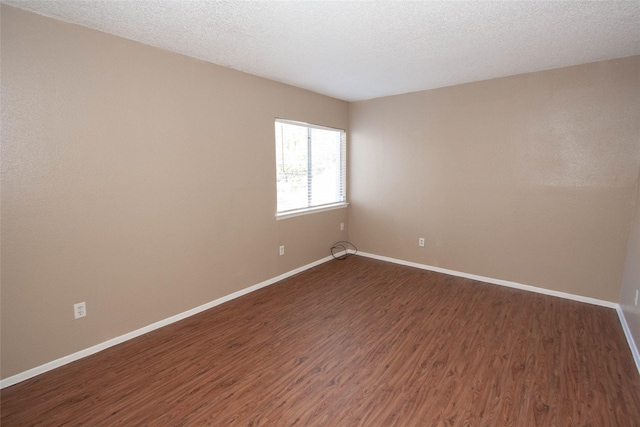 unfurnished room with dark wood-type flooring and a textured ceiling