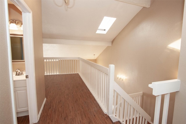 hall with vaulted ceiling with skylight and dark hardwood / wood-style flooring