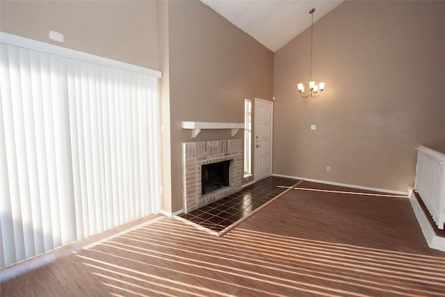 unfurnished living room featuring a brick fireplace, lofted ceiling, and an inviting chandelier