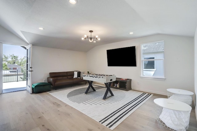 playroom featuring plenty of natural light, light hardwood / wood-style flooring, lofted ceiling, and a notable chandelier