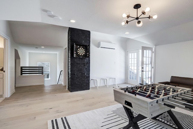 playroom with a wall mounted air conditioner, a notable chandelier, light hardwood / wood-style floors, and vaulted ceiling